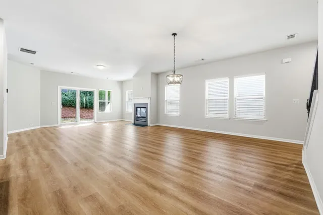 a view of an empty room with window and wooden floor