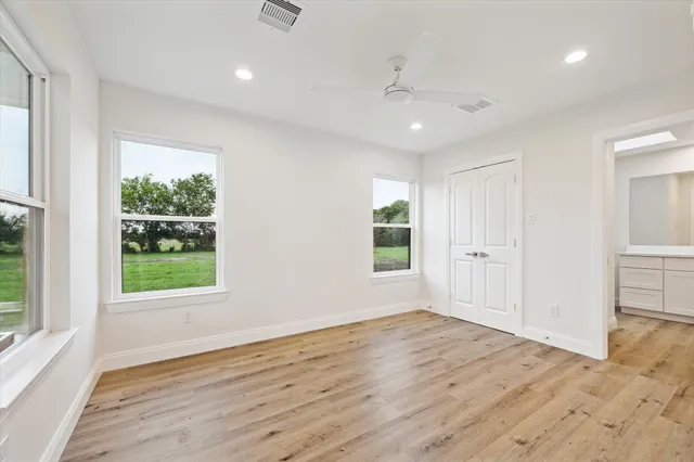 an empty room with wooden floor and windows