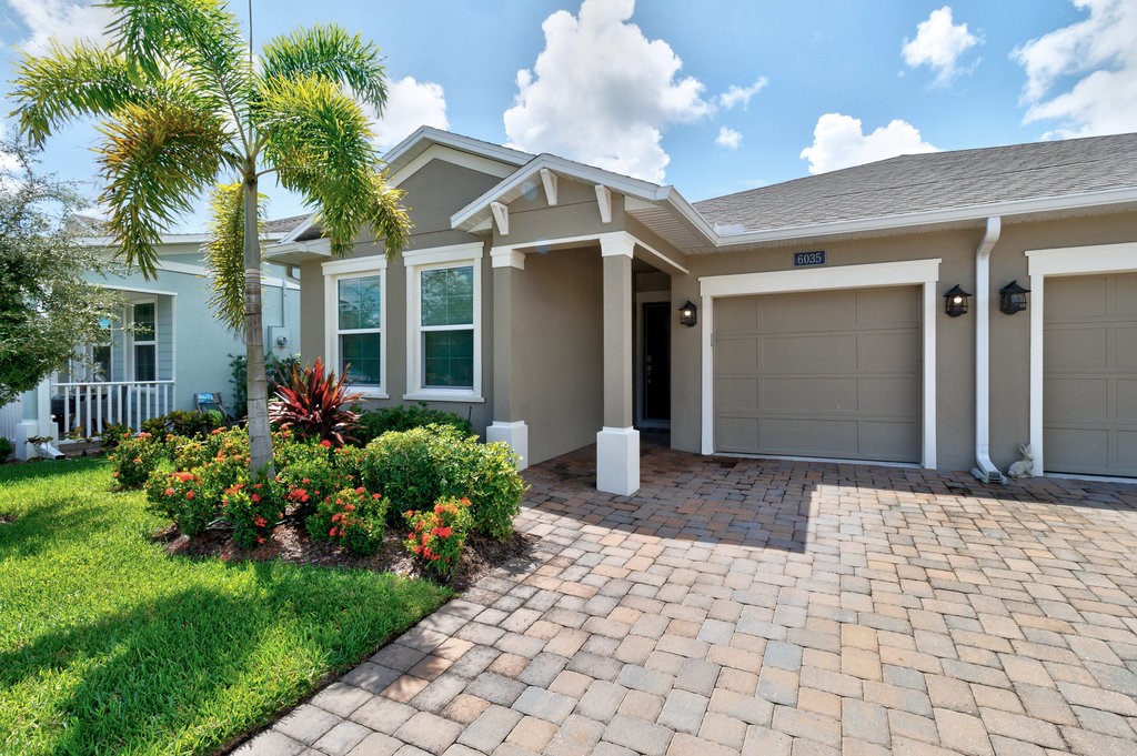 6035 Red Maple Manor Vero Beach, FL 32966 - Photo 3 of 36 a front view of a house with a yard and potted plants