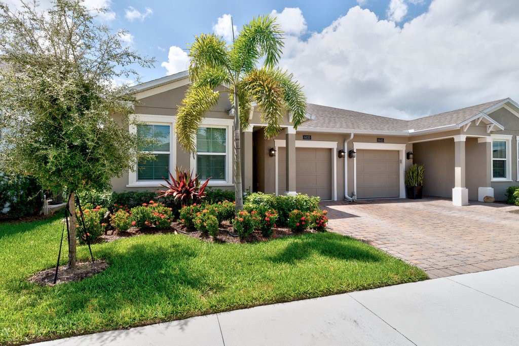 6035 Red Maple Manor Vero Beach, FL 32966 - Photo 4 of 36 a front view of a house with a garden and plants