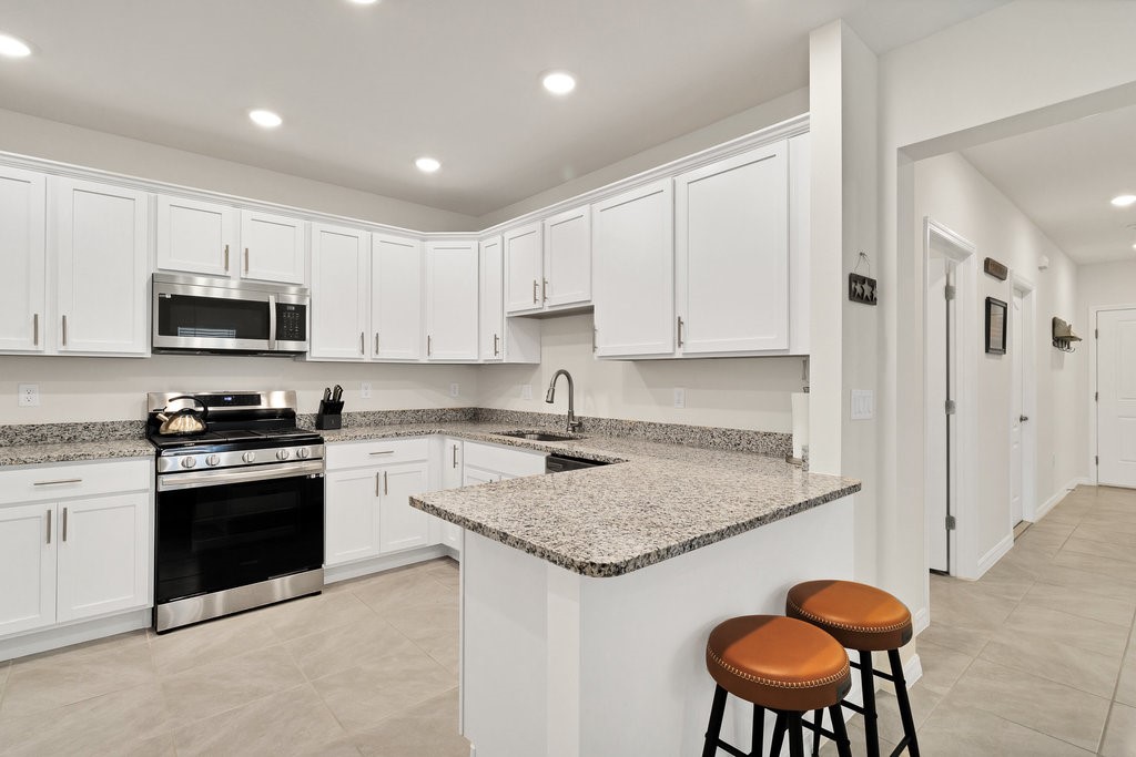 6035 Red Maple Manor Vero Beach, FL 32966 - Photo 10 of 36 a kitchen with stainless steel appliances granite countertop a stove a sink a microwave a refrigerator and white cabinets