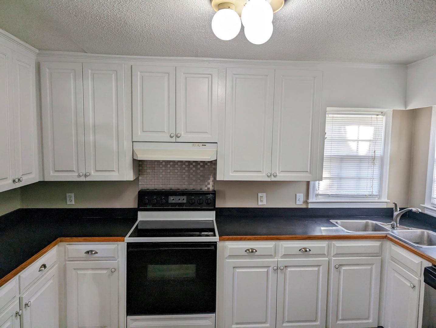 a kitchen with granite countertop white cabinets and a stove