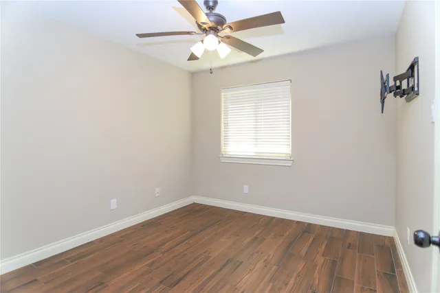 an empty room with a window and a ceiling fan