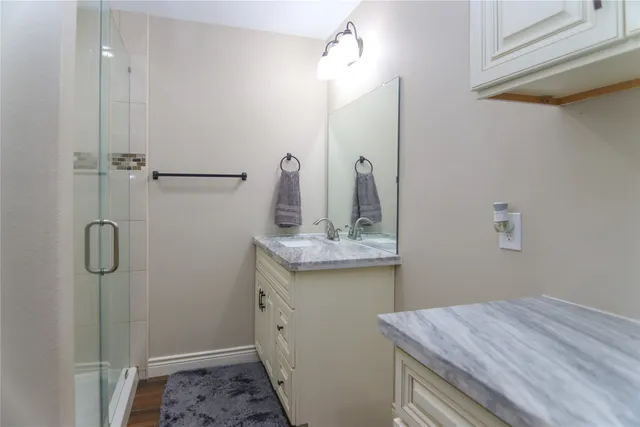 a bathroom with a granite countertop sink a mirror and shower