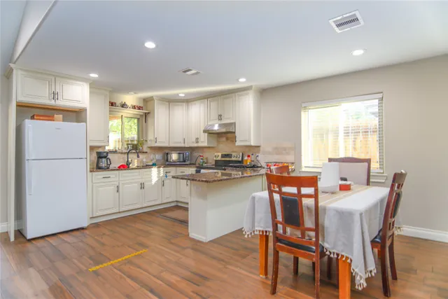 a kitchen with a table chairs refrigerator and microwave