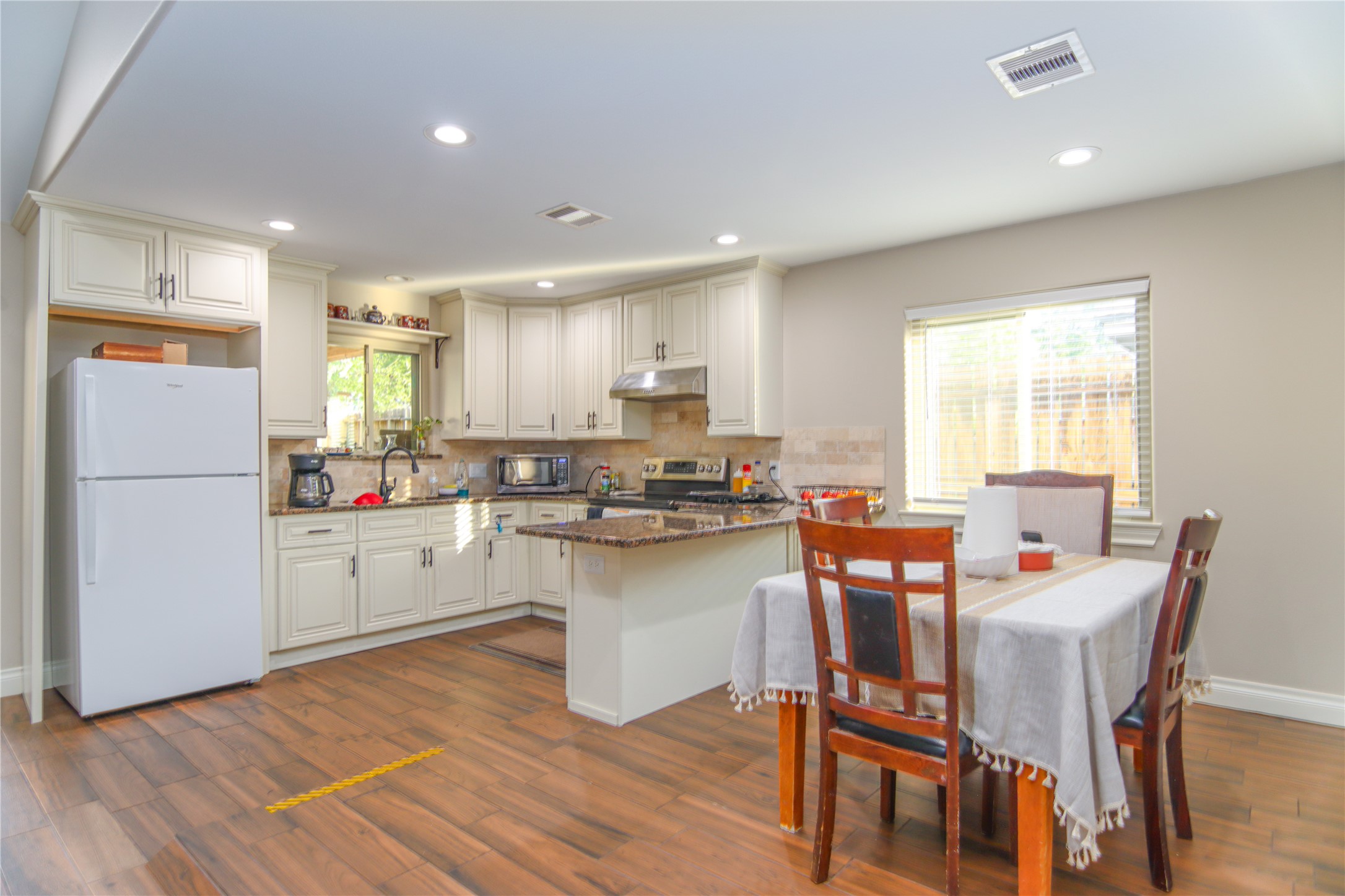 9710 Wind Flower Lane Houston, TX 77086 - Photo 4 of 21 a kitchen with a table chairs refrigerator and microwave