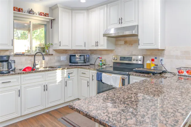 a kitchen with stainless steel appliances granite countertop a sink stove and cabinets