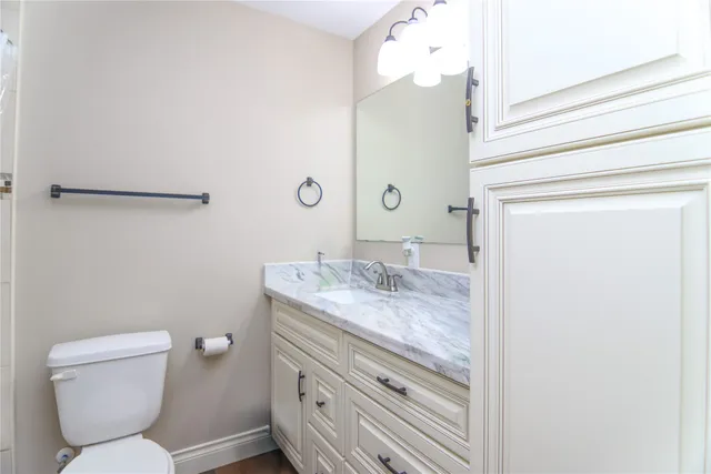 a bathroom with a granite countertop toilet sink and mirror