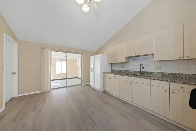 a kitchen with granite countertop white cabinets a sink and dishwasher with wooden floor