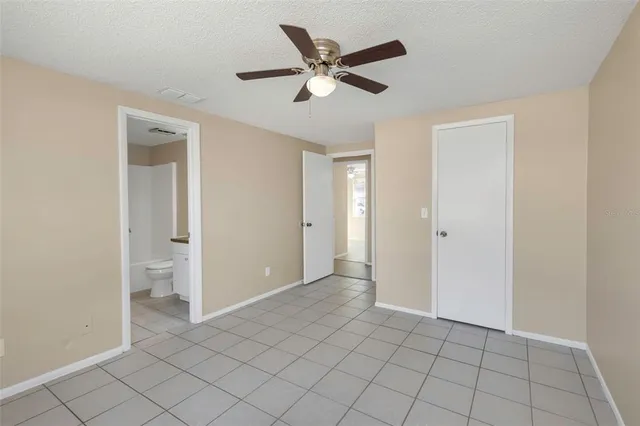 a view of an empty room and cabinet with a ceiling fan