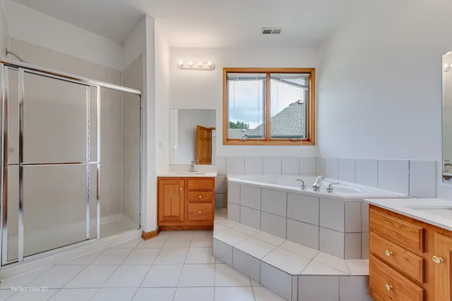 a bathroom with a double vanity sink a mirror and a bathtub