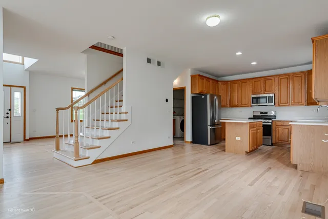 a view of kitchen with stainless steel appliances kitchen island wooden cabinets and wooden floor