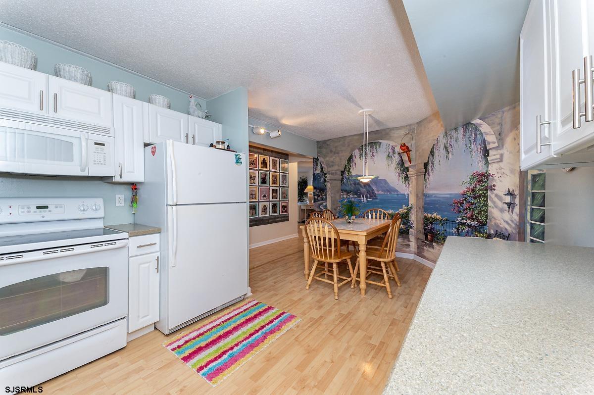 935 Ocean Avenue, Unit 315 Ocean City, NJ 08226 - Photo 12 of 37 a kitchen with stainless steel appliances a stove a refrigerator and a dining table with wooden floor