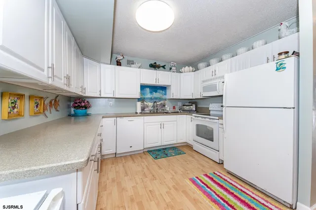 a kitchen with granite countertop white cabinets and white appliances