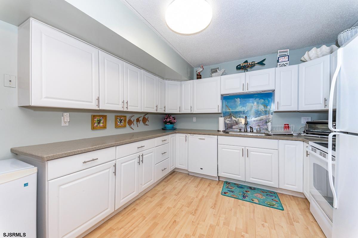 935 Ocean Avenue, Unit 315 Ocean City, NJ 08226 - Photo 10 of 37 a kitchen with cabinets appliances a sink and a counter top space