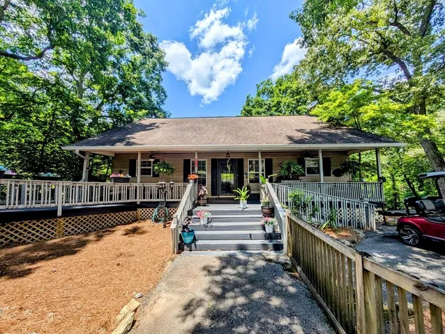 a view of a patio with couches table and chairs under an umbrella with large trees