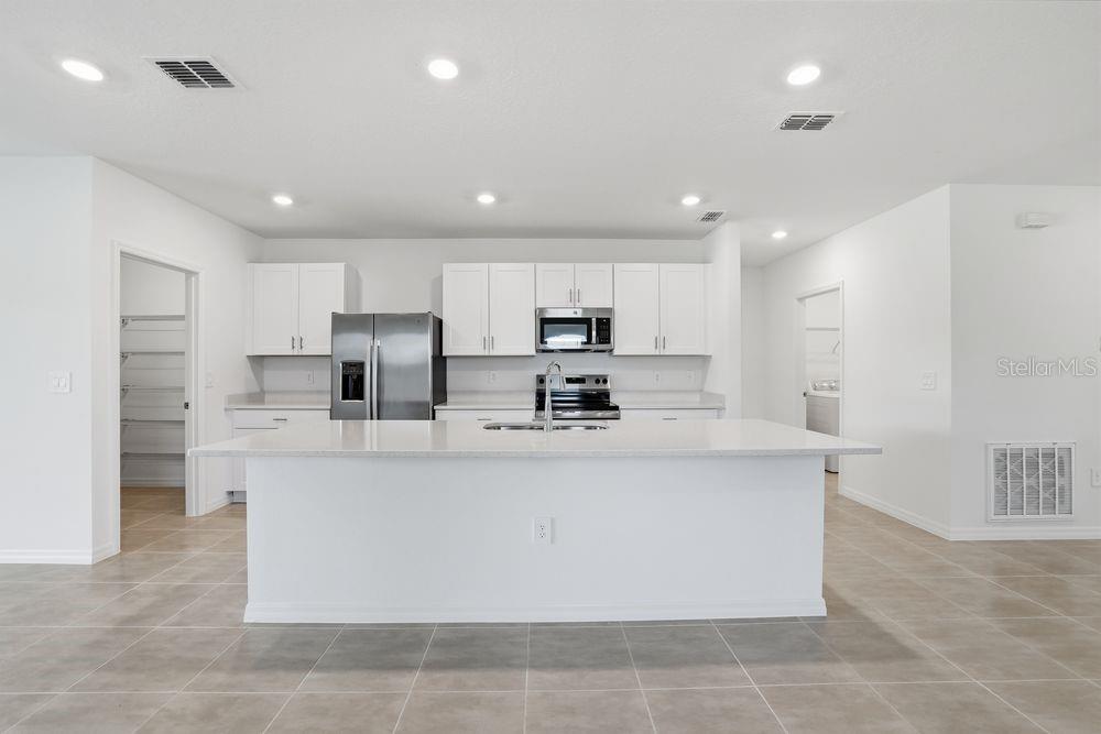 13640 Tropical Breeze Way Hudson, FL 34669 - Photo 2 of 48 a large kitchen with stainless steel appliances granite countertop a stove a sink a refrigerator and white cabinets with wooden floor