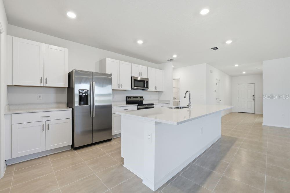 13640 Tropical Breeze Way Hudson, FL 34669 - Photo 8 of 48 a large kitchen with stainless steel appliances a refrigerator a sink dishwasher with a stove and white cabinets