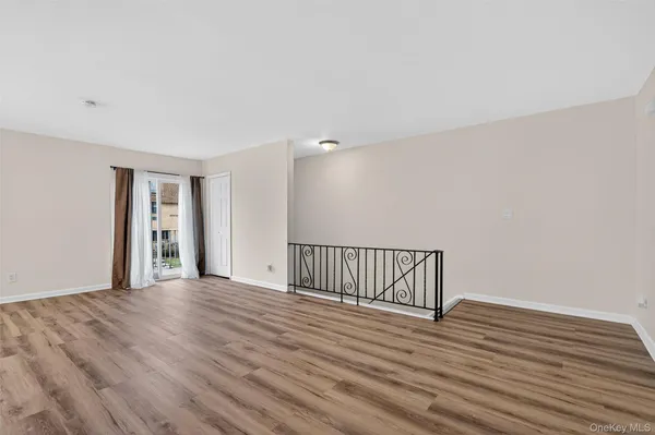 a view of an empty room with wooden floor and fan
