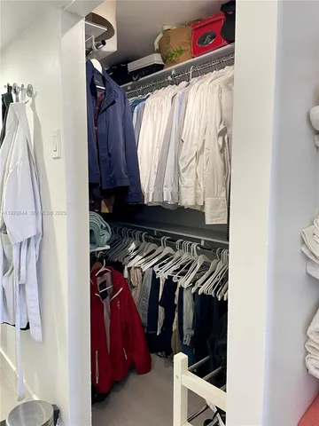 a view of walk in closet with clothes and shoes