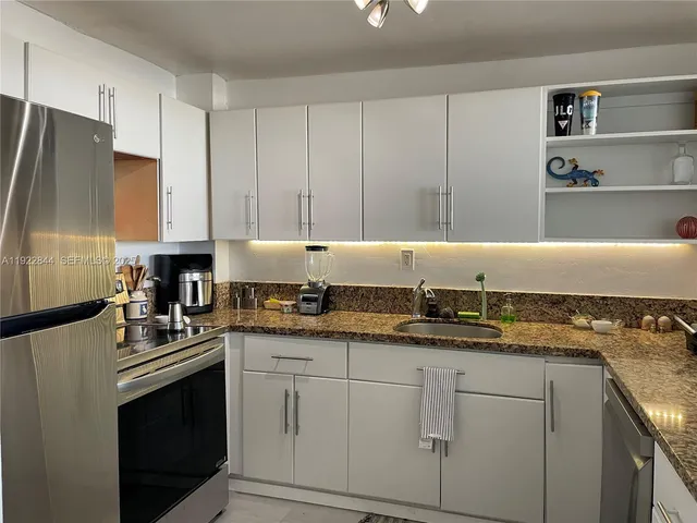 a kitchen with granite countertop a sink a stove and cabinets