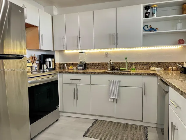 a kitchen with granite countertop white cabinets and white appliances