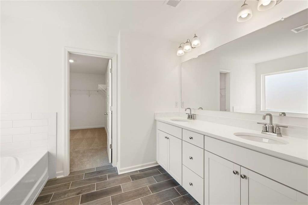 1851 Lacebark Elm Way Lawrenceville, GA 30045 - Photo 35 of 63 a spacious bathroom with a double vanity sink a mirror and a bathtub