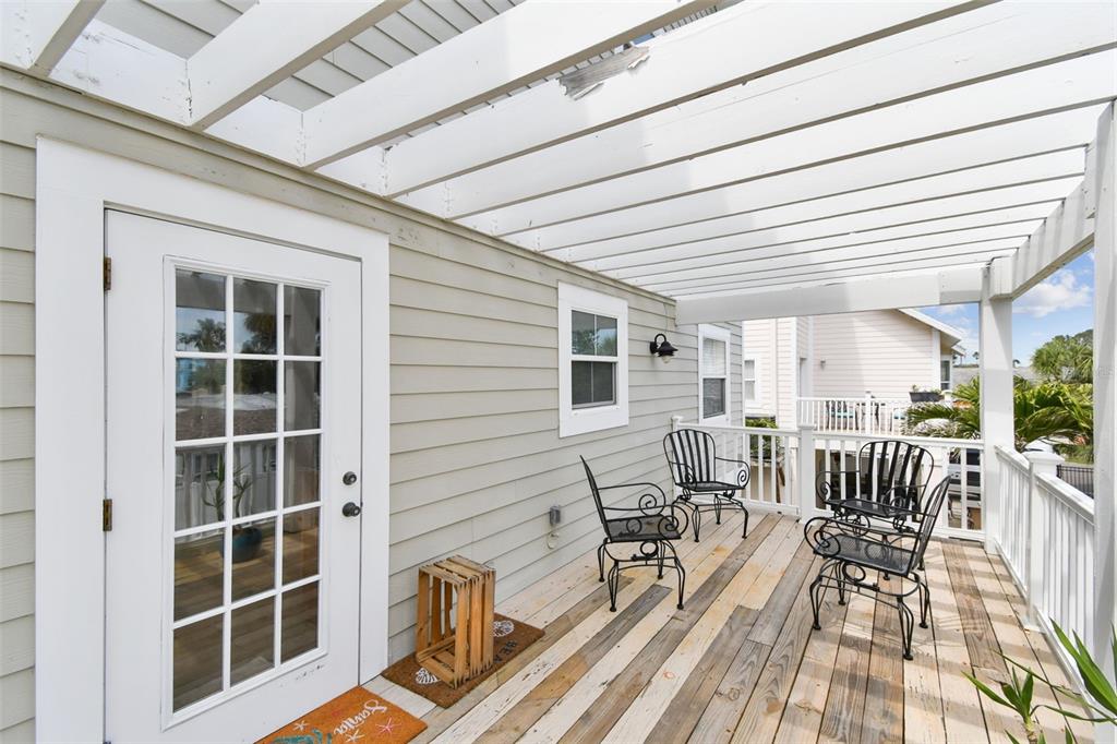 16033 Gulf Boulevard Redington Beach, FL 33708 - Photo 23 of 98 a view of a patio with table and chairs with wooden floor and fence