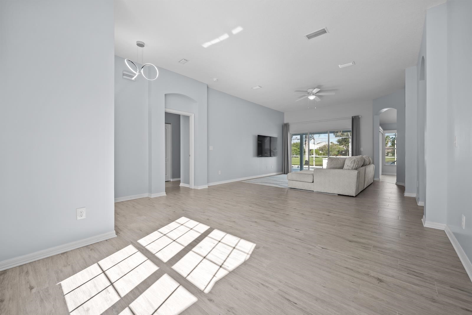1116 Compass Row St. Augustine, FL 32080 - Photo 13 of 68 Unfurnished living room with arched walkways, a ceiling fan, and light wood-style floors