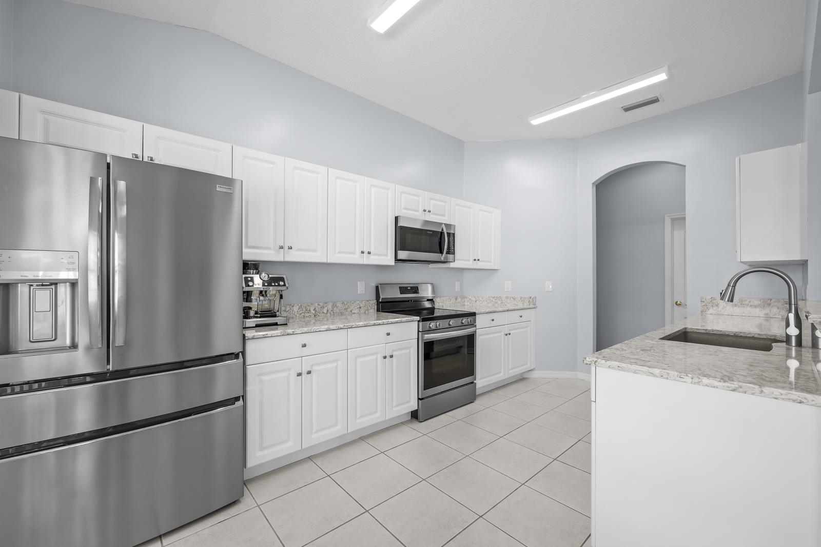 1116 Compass Row St. Augustine, FL 32080 - Photo 16 of 68 Kitchen featuring stainless steel appliances, light stone countertops, white cabinets, and lofted ceiling
