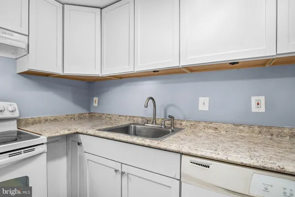 a kitchen with granite countertop white cabinets and a sink