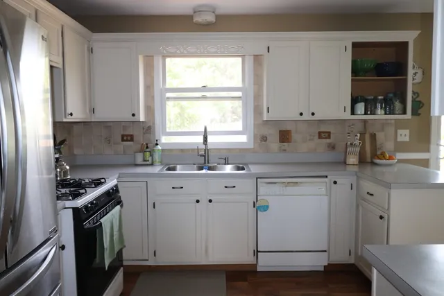 a kitchen with cabinets appliances a sink and a window