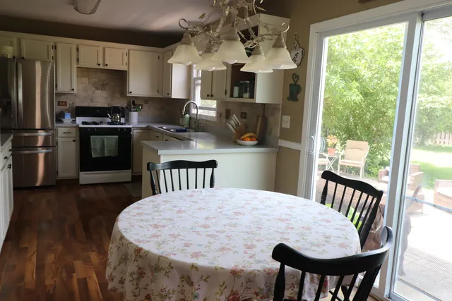 a kitchen with stainless steel appliances granite countertop a stove a refrigerator a dining table and chairs with wooden floor