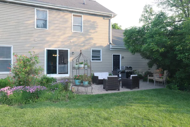 a backyard of a house with wooden chairs and potted plants