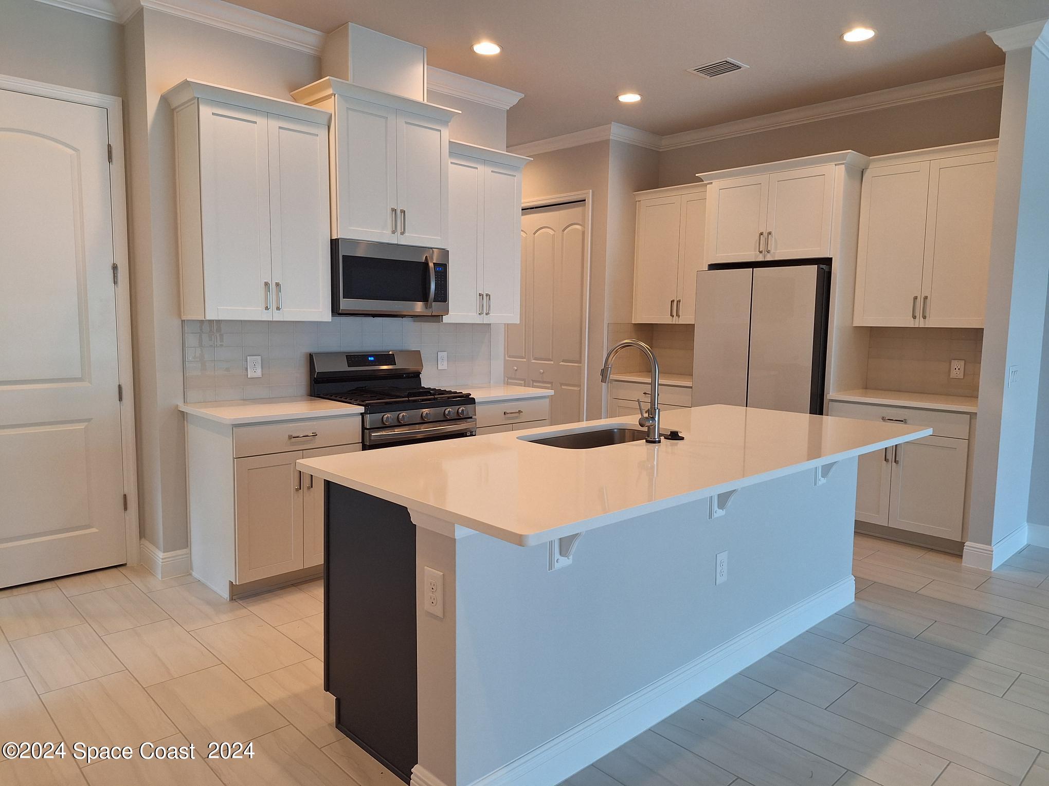 7929 Cache Crk Lane Melbourne, FL 32940 - Photo 5 of 33 a kitchen with kitchen island a sink stainless steel appliances and cabinets