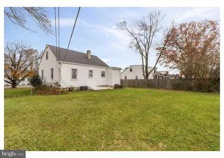 a view of a white house with a big yard and large tree