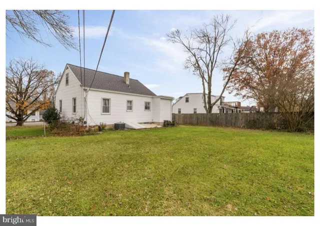 a view of a white house with a big yard and large tree
