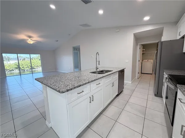 a kitchen with granite countertop a sink a counter top space appliances and cabinets