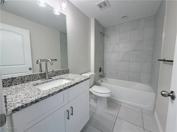 a bathroom with a granite countertop sink a toilet and bathtub