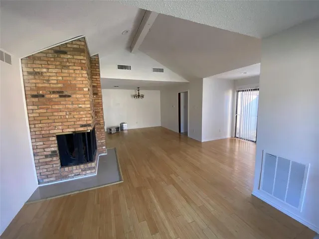 a view of an empty room with wooden floor fireplace and a window
