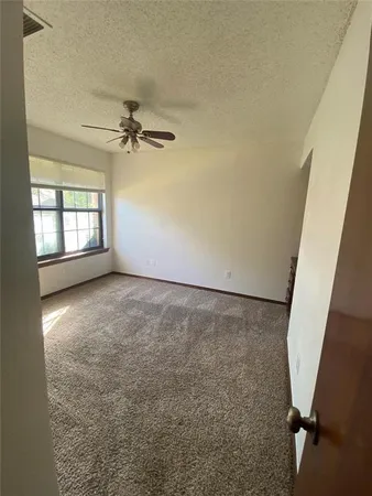 an empty room with windows and fan