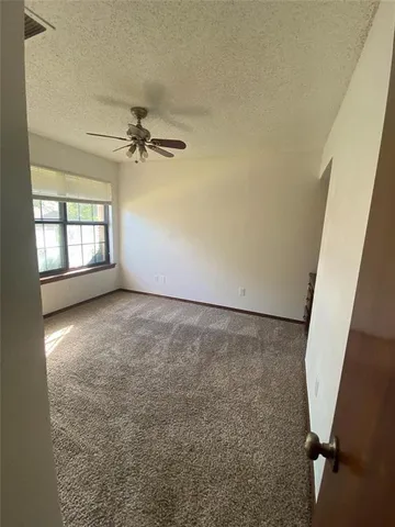 an empty room with windows and fan