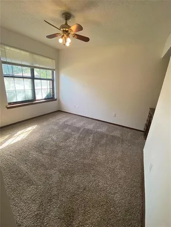 an empty room with windows and ceiling fan