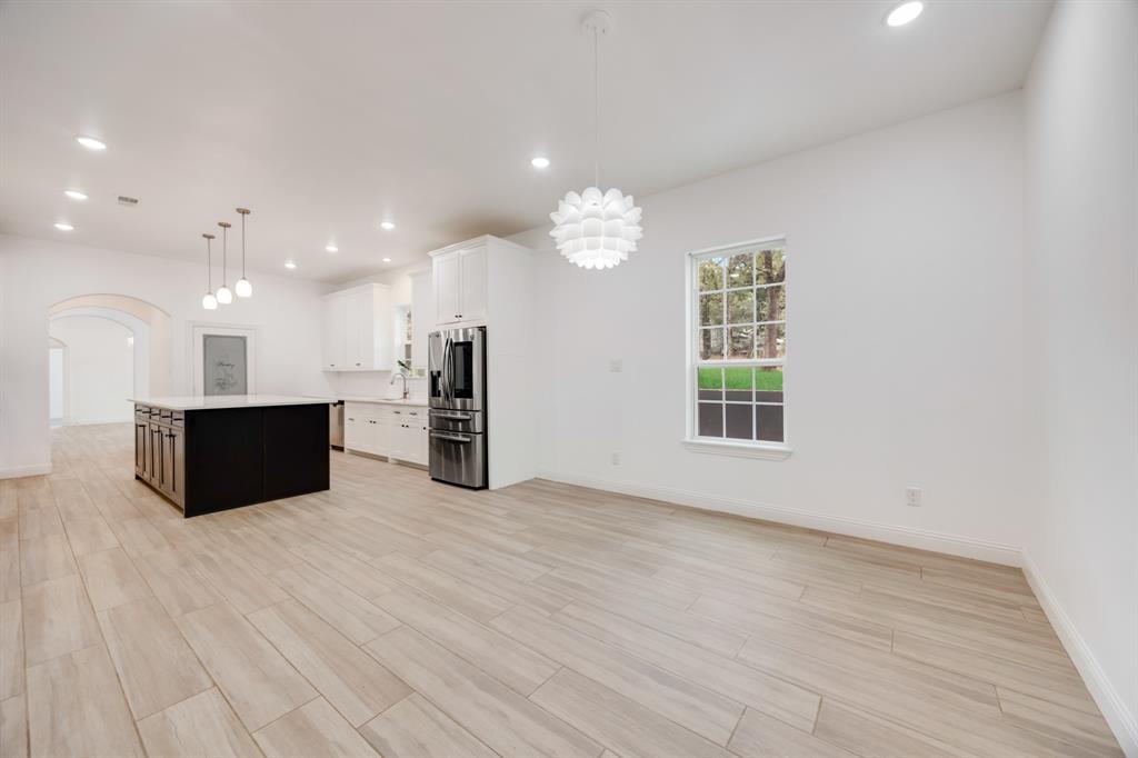 1016 Silver Creek Azle Road Azle, TX 76020 - Photo 13 of 40 Kitchen with a center island, light countertops, arched walkways, stainless steel fridge, and light wood-type flooring