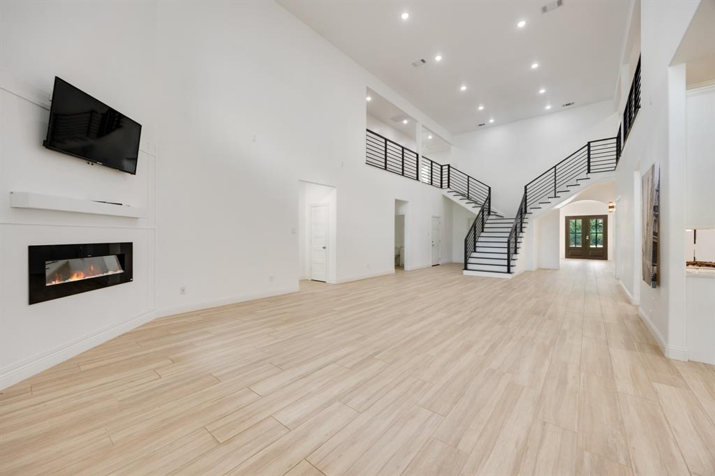 1016 Silver Creek Azle Road Azle, TX 76020 - Photo 7 of 40 Unfurnished living room featuring a glass covered fireplace, a towering ceiling, stairway, recessed lighting, and light wood-type flooring