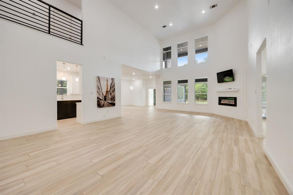 1016 Silver Creek Azle Road Azle, TX 76020 - Photo 8 of 40 Unfurnished living room with a towering ceiling, light wood finished floors, and a glass covered fireplace