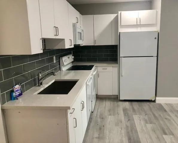 a kitchen with a sink a refrigerator and cabinets