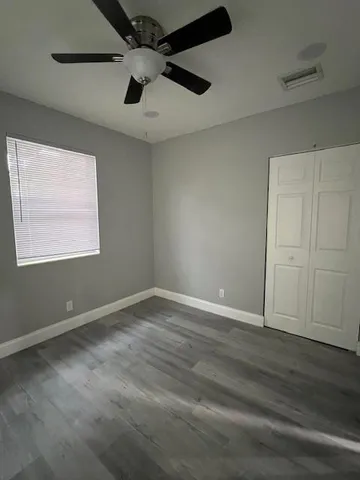 en empty room with wooden floor ceiling fan and windows