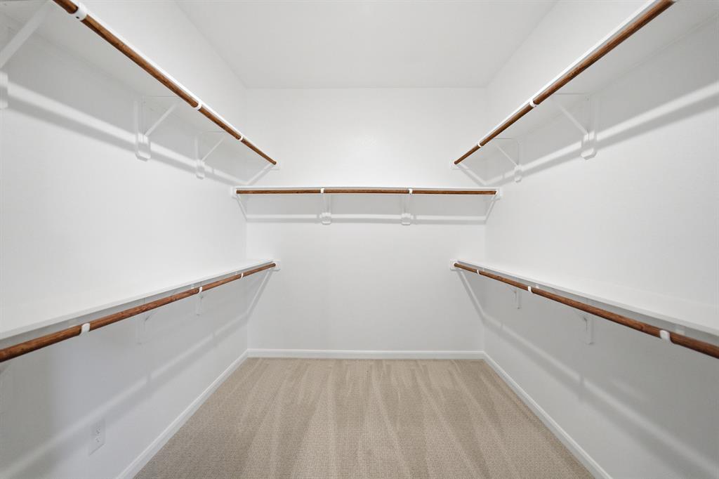 1908 Sangallo Lane Celina, TX 75009 - Photo 18 of 35 Walk-in closet featuring light beige carpeting, white walls, multiple built-in shelving units, and wood-finish hanging rods