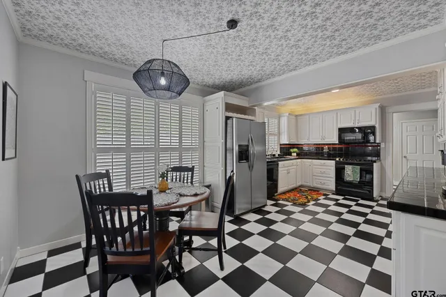 a kitchen with stainless steel appliances granite countertop a dining table chairs and a refrigerator
